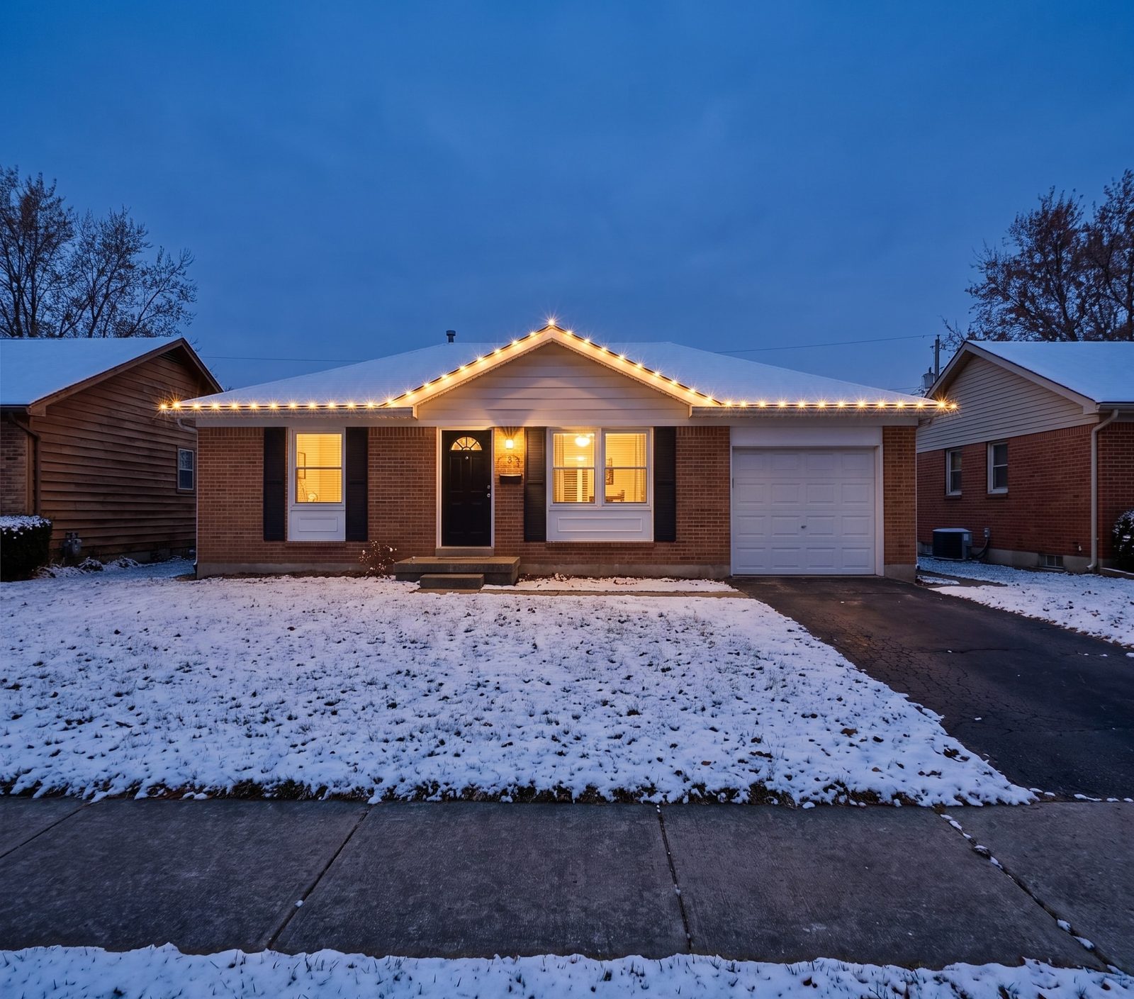 A single-storey house lit at twilight while the houses on either side stay dark